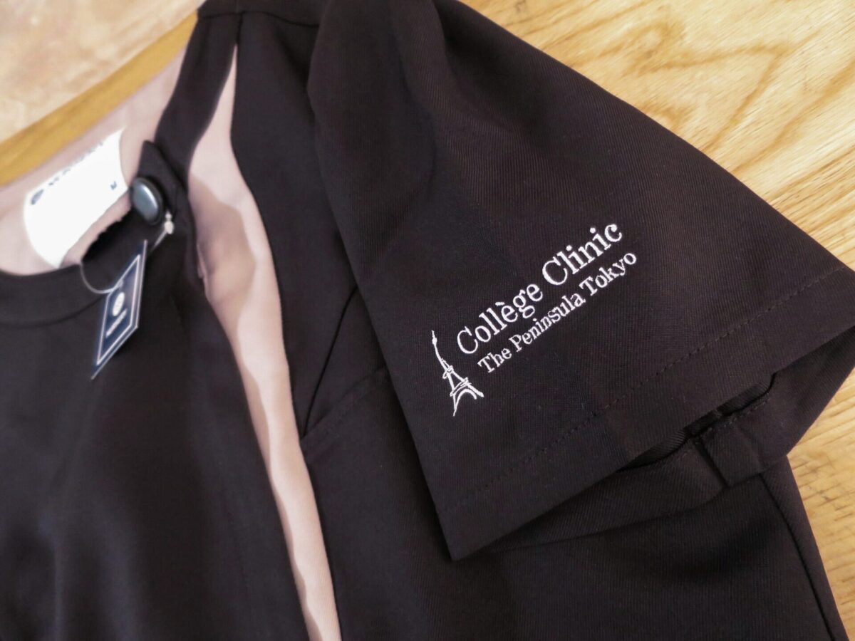 スクラブの袖に施したロゴ刺繍。黒地のスクラブに白糸でクリニック名とエッフェル塔モチーフを刺繍したユニフォームの制作実績