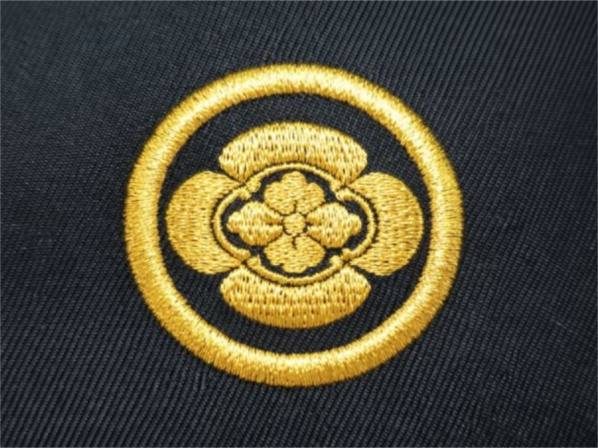 黒地の生地に金糸で円形の家紋を刺繍した高級感のある刺繍加工