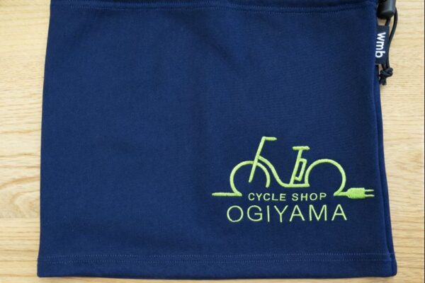 ネイビーのネックウォーマーに、サイクルショップOGIYAMAの自転車モチーフロゴを黄緑色の刺繍で入れたオリジナル刺繍実績