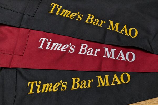黒と赤のエプロンに店名「Time's Bar MAO」を大きく刺繍した飲食店ユニフォーム