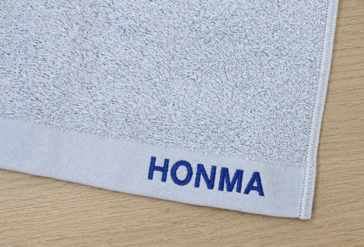 HONMAの名入れ刺繍を施したグレーの今治タオル。お中元・お歳暮・法人ギフト向けオリジナル刺繍制作事例。