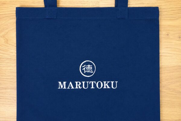 ネイビーのキャンバスエコバッグに白糸でMARUTOKUの企業ロゴを刺繍したオリジナルエコバッグの制作事例