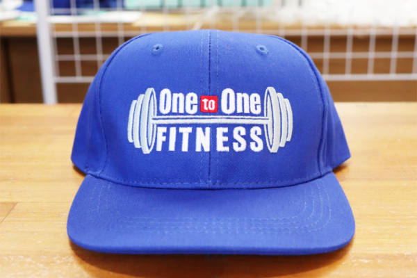 パーソナルジム「One to One FITNESS」のロゴを刺繍したブルーのオリジナルキャップ