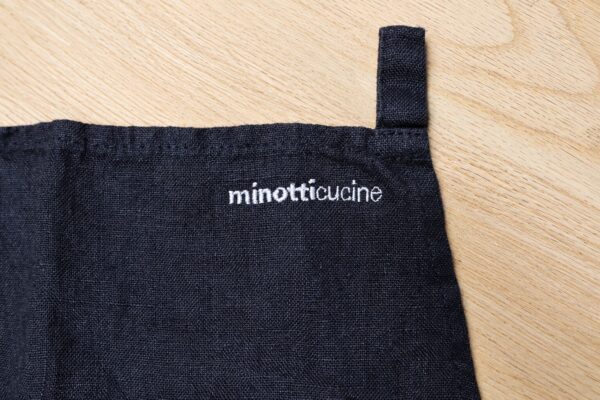 麻素材の黒いエプロンに高さ5mmの細かなロゴ文字を白糸で刺繍したオリジナルエプロン