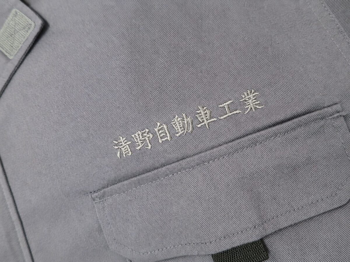 お持ち込みのサロペット胸ポケット上に会社名を刺繍した作業服刺繍。お急ぎのご依頼にも対応したオリジナル社名刺繍。