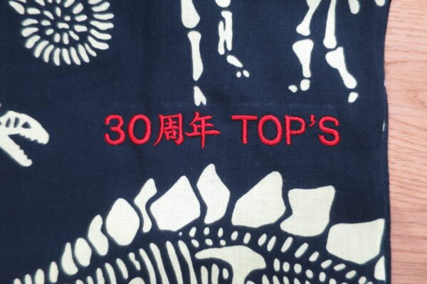 濃紺の手拭いに「30周年 TOP’S」の文字を赤糸で刺繍した周年記念品