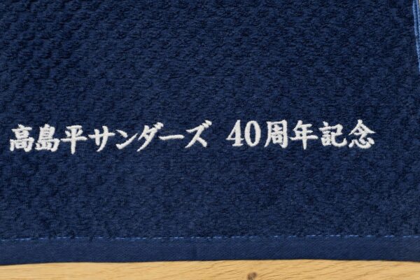 濃紺の持ち込みタオルに「高島平サンダーズ 40周年記念」の文字を白糸で刺繍した記念品