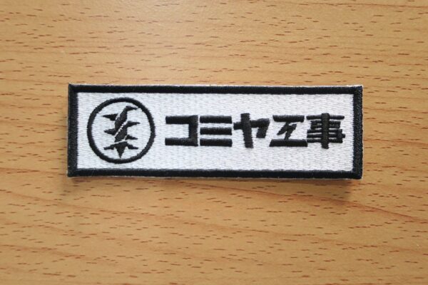 東京都大田区のコミヤ工事有限会社様よりリピートでご注文いただいた社名入りオリジナル刺繍ワッペン。白ツイル生地に黒糸で社名を刺繍した作業服用ワッペン。