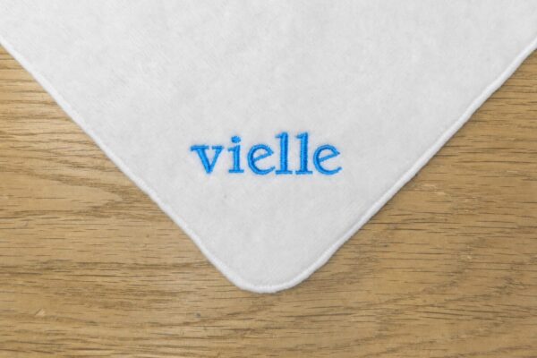 白いハンドタオルの角に「vielle」の文字をコバルトブルーの糸で刺繍した販促品