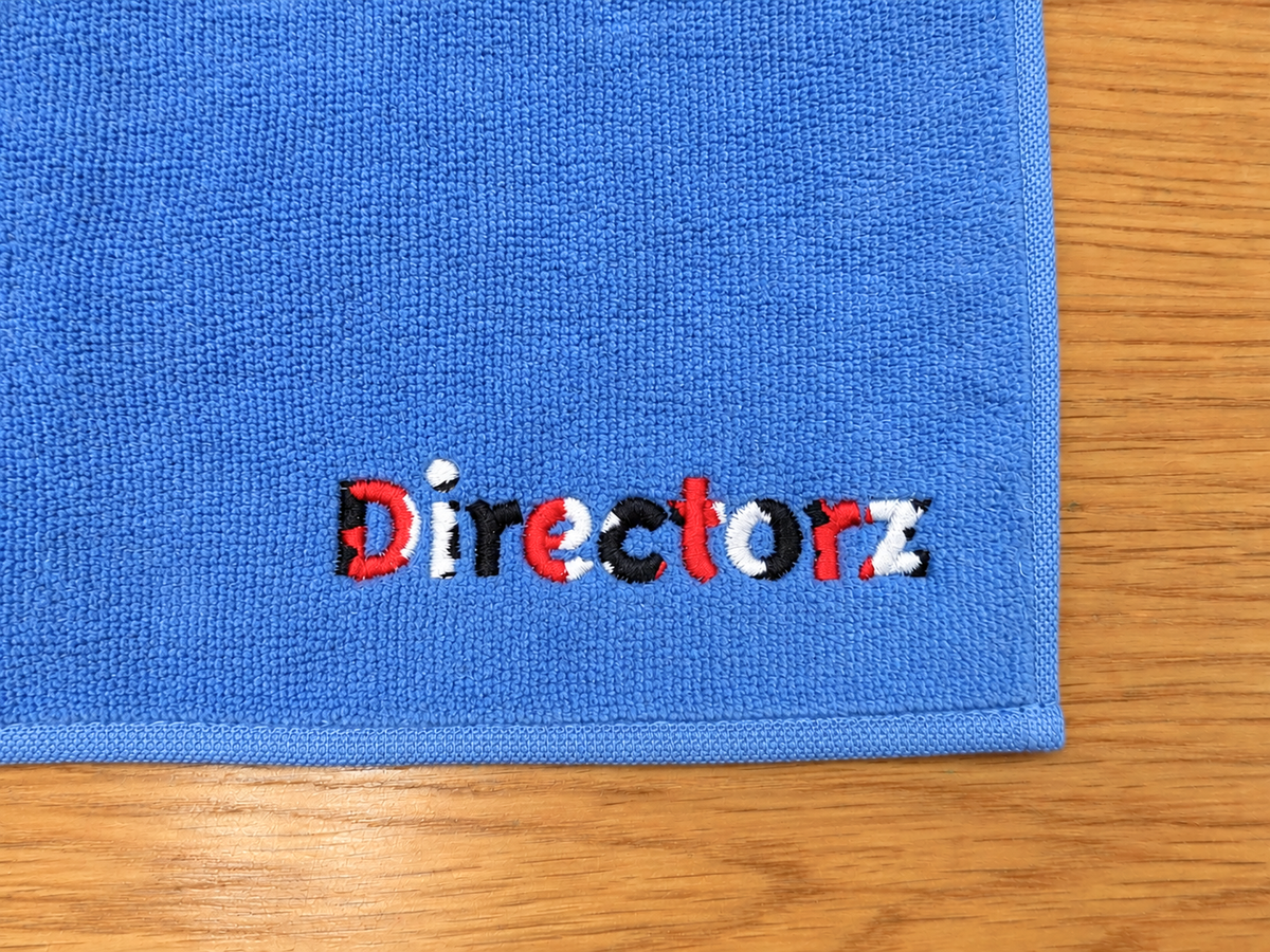 青のハンドタオルにDirectorzの文字を赤・黒・白で刺繍した販促品の制作事例