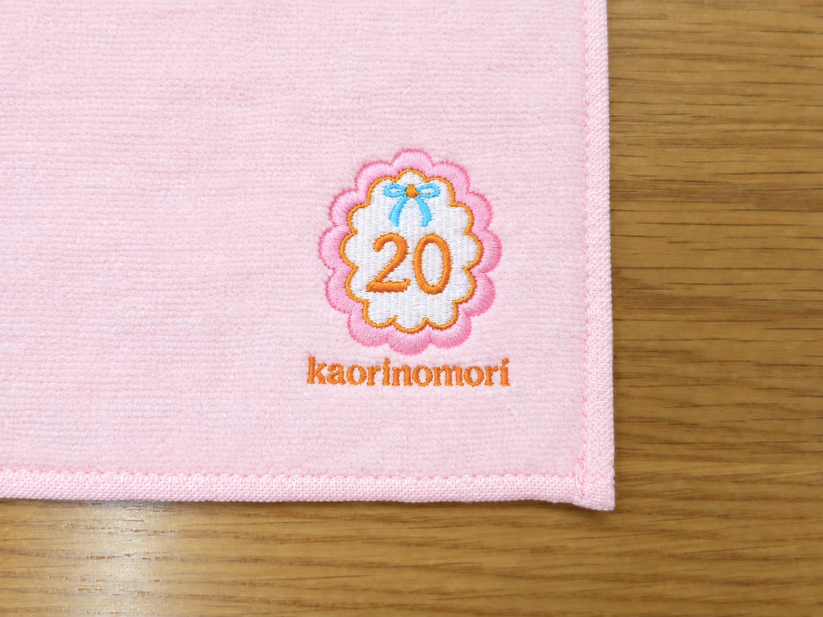 販促用ハンドタオルに20の花柄デザインとkaorinomoriの文字を多色刺繍した制作事例