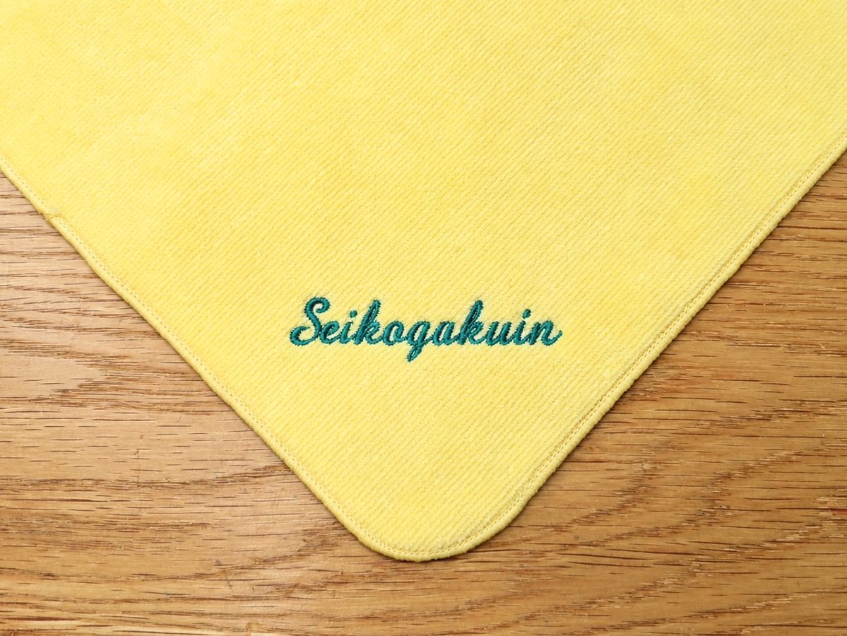 聖光学院様の記念品として黄色のハンドタオルにSeikogakuinの文字を刺繍した制作事例